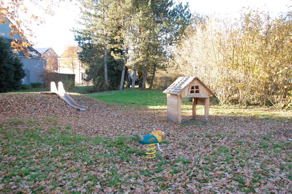 Het ‘boerendorp’ met de speelheuvel met glijbaan, de schommelkip en het dorpshuisje. 