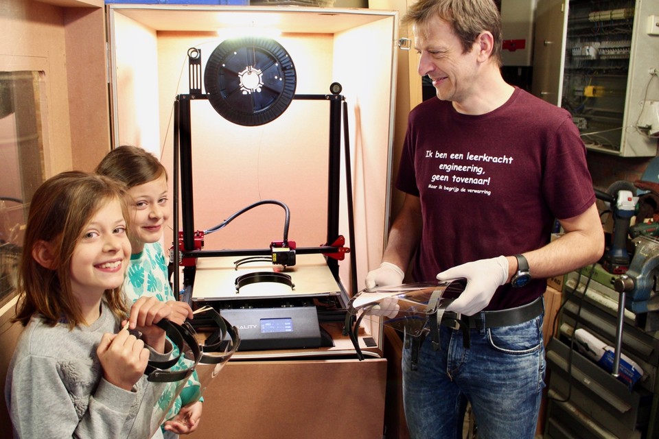 Leerkracht Erik Marynissen en zijn tweelingdochters Lena en Milla voor zijn zelf ontworpen de 3D-printer 