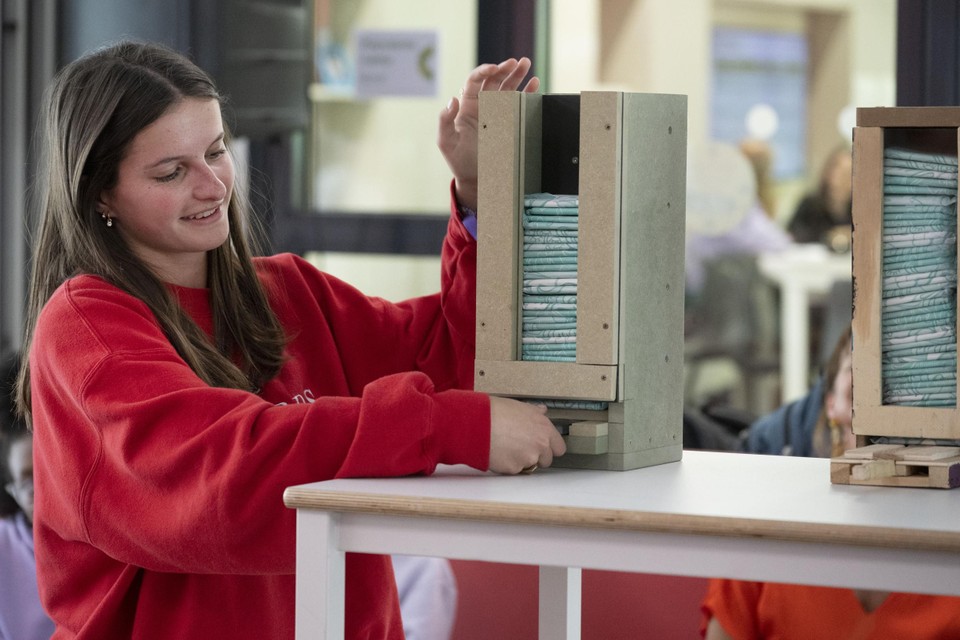Scholier Floor Vanharen test de zelfontworpen automaat met maandverbanden uit op haar school SMIK in Kasterlee. 