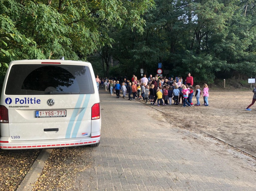 De kinderen verzamelen op de zanderige parking.