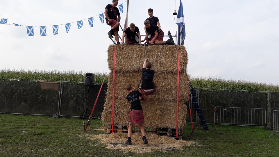Strobaalklimmen in Schotse rokken op Highlandgames.