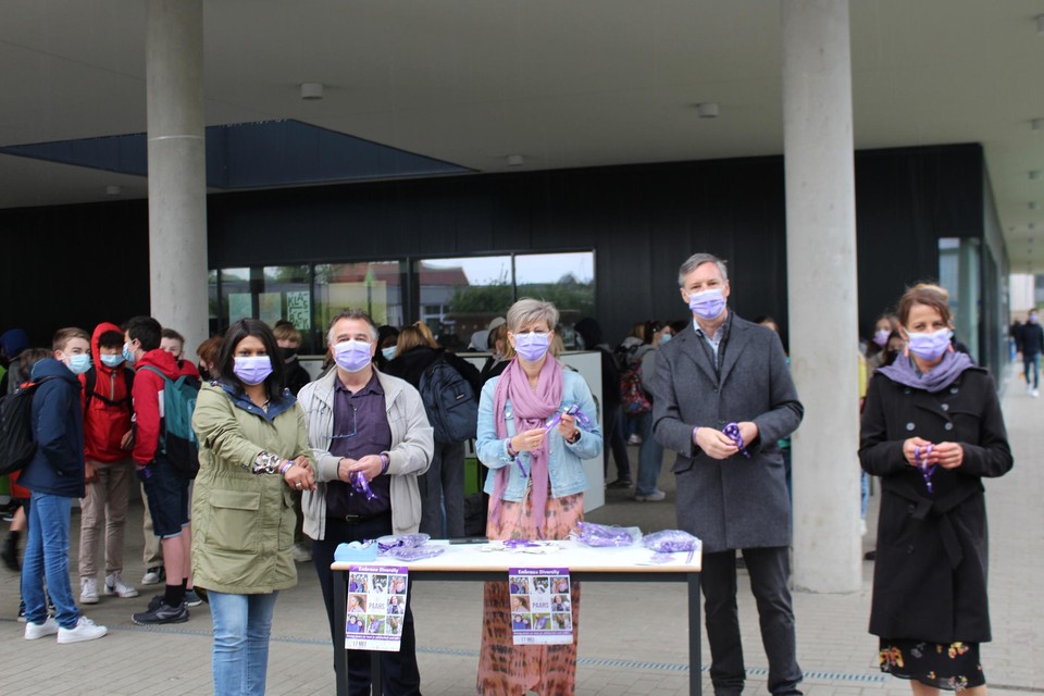 Directieleden van SMIK en leden van het schepencollege in Kasterlee delen paarse armbandjes uit.