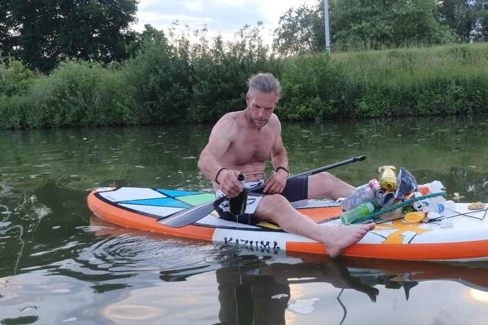 Dirk Van de Velde monstert een fles bubbels die hij uit het water vist.