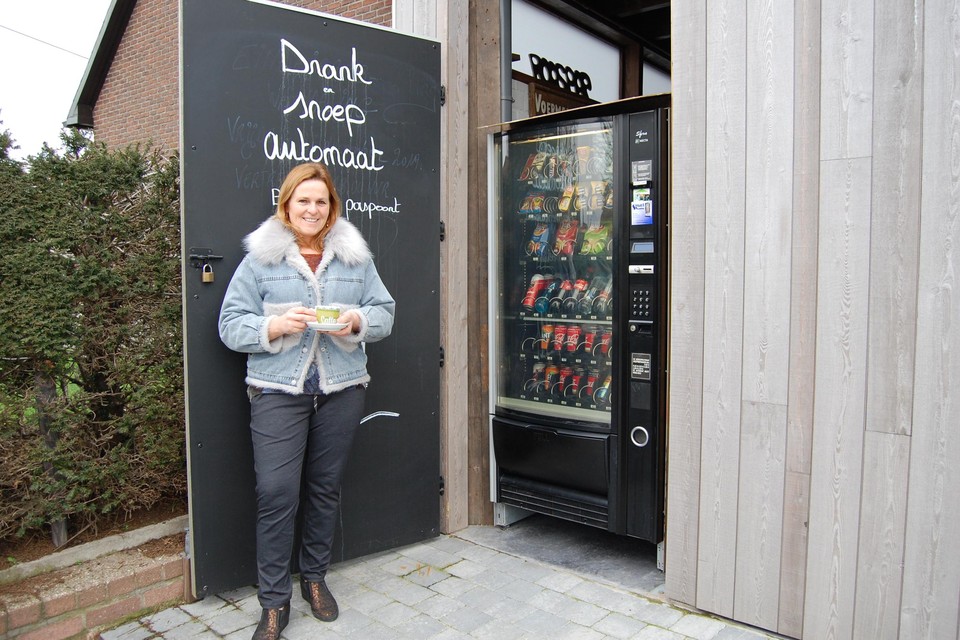 Marleen van café De Voermansrust bij haar gloednieuwe drank- en snoepautomaat. 