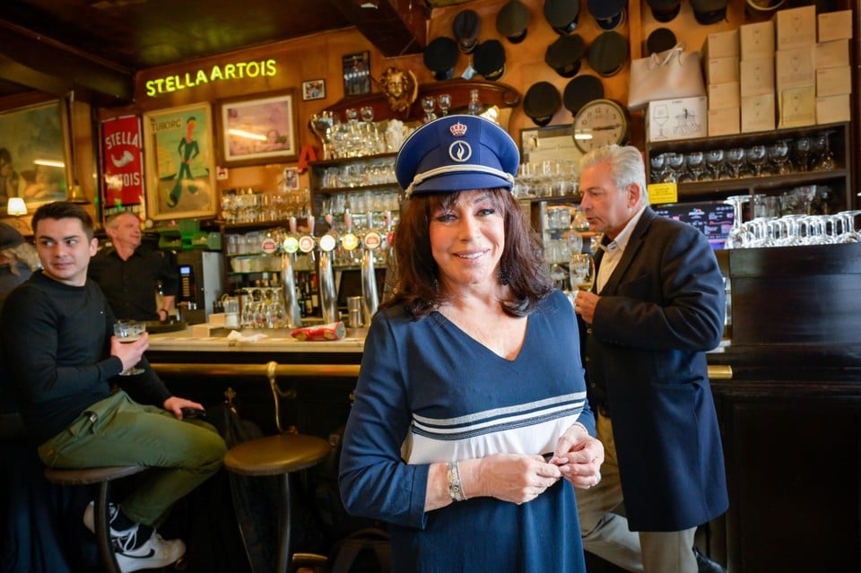 Cafébazin van Den Engel, Linda Van Heymbeeck met de pet van een politieagent die enkele jaren geleden met pensioen ging. Op de achtergrond hangen de ‘klakken’ van postbodes die er letterlijk hun ‘klak aan de haak hingen’ 