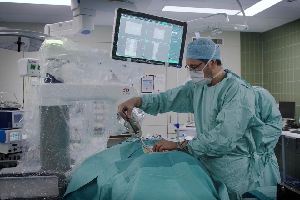 Neurochirurg Bert Kegelaers is aan het werk met de genavigeerde robotarm in een van de operatiezalen. 