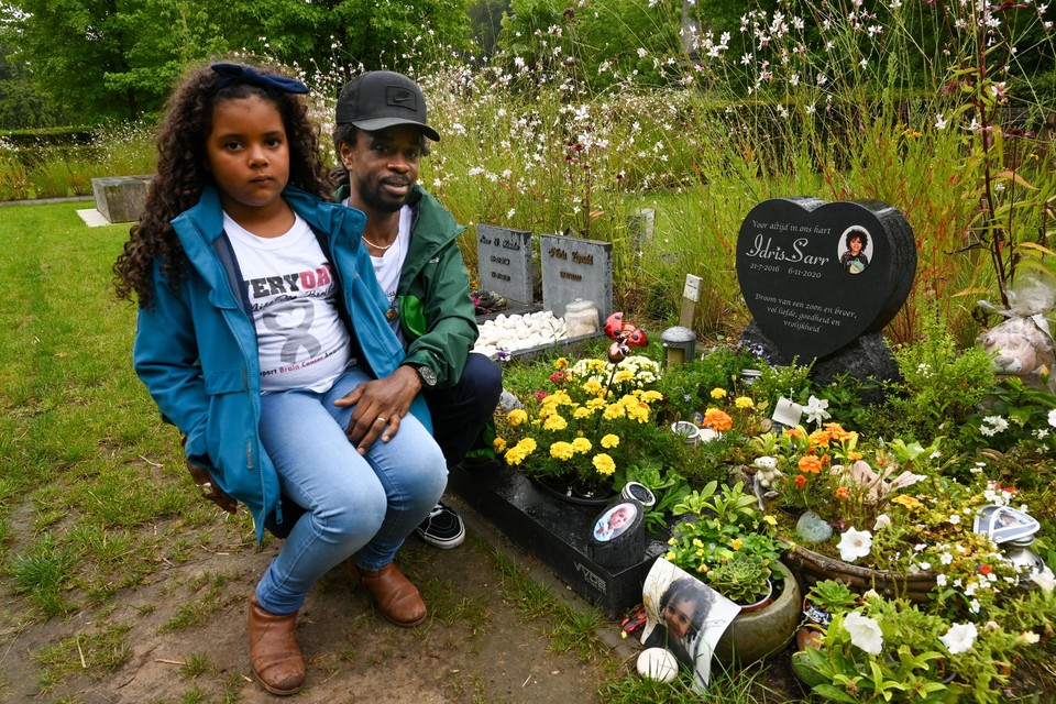 Zus Awa (8) en papa Ibrahima (42) bij het graf van Idris, dat ze samen met mama Thara (34) overladen met bloemen en speelgoed.  