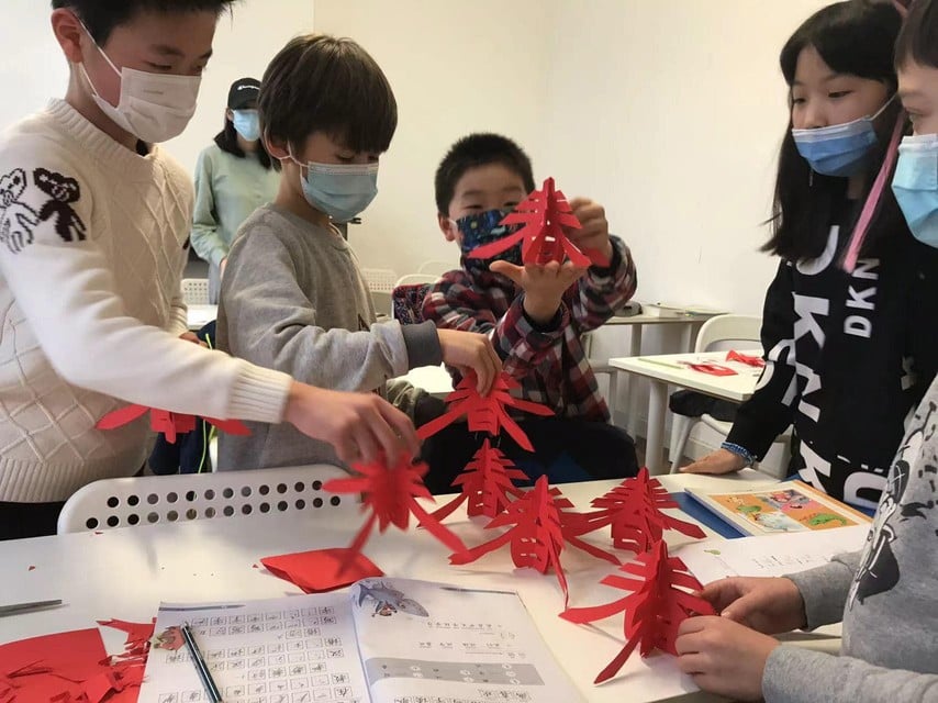 Leerlingen knippen een 3D-vorm uit van het Chinese karakter voor lente. 