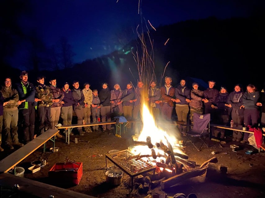 Leiding van de scoutsgroep 99ste Parsifal Wijnegem verzameld rond het kampvuur tijdens een vorig, winters samenzijn eerder dit jaar. 