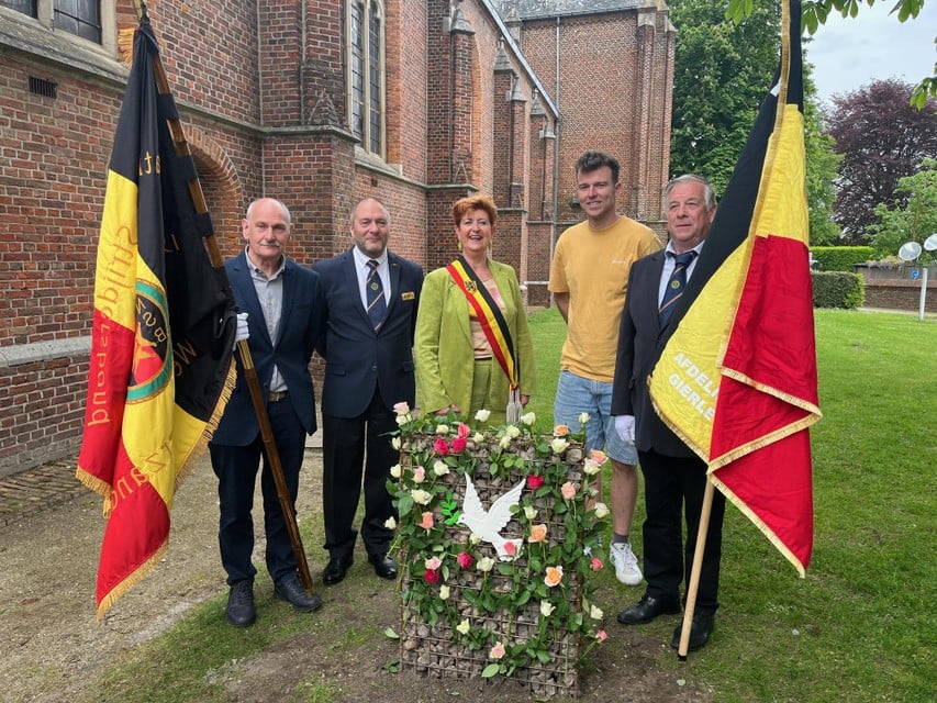 Luc Bouvin van NSB staat samen met burgemeester Marleen Peeters, schepen Chiel Danckers en twee vaandeldragers bij het vredesmonument in Gierle.