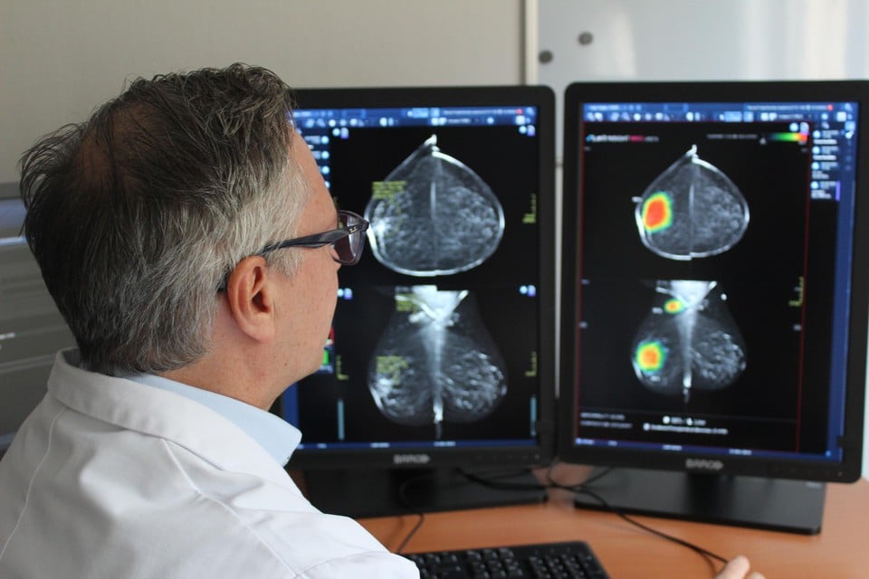 Dokter De Schepper bekijkt een mammografie waaropo AI software via een ‘heat map’ de risicozones aangeeft.