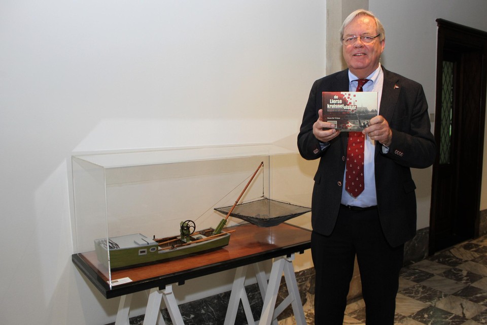 Koen De Vriese staat met zijn boek bij het model van een Lierse palingschuit, gebouwd door de School voor Scheepsmodelbouw.