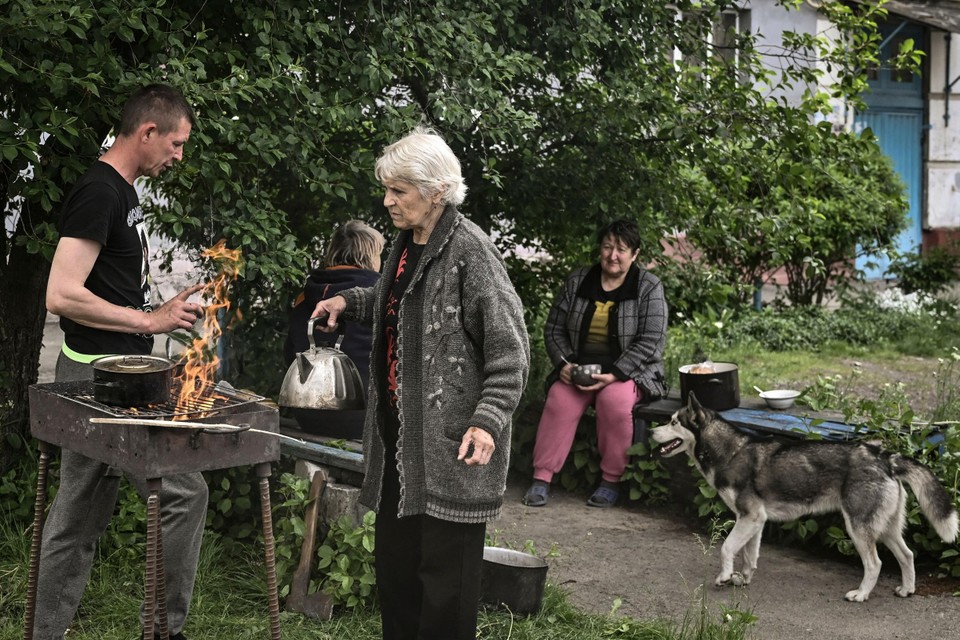 Inwoners van Lysychansk koken buiten op een vuurtje. Elektriciteit en water is er niet in hun huizen.  