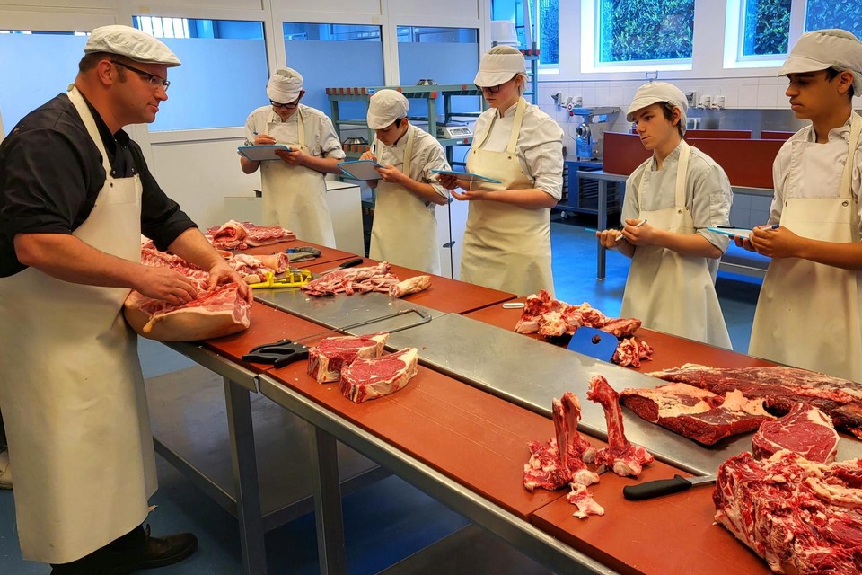Leerkracht Slagerij Frank Kimpen onderwijst zijn leerlingen in de verschillende onderdelen die je uit een groot stuk vlees kunt snijden.
