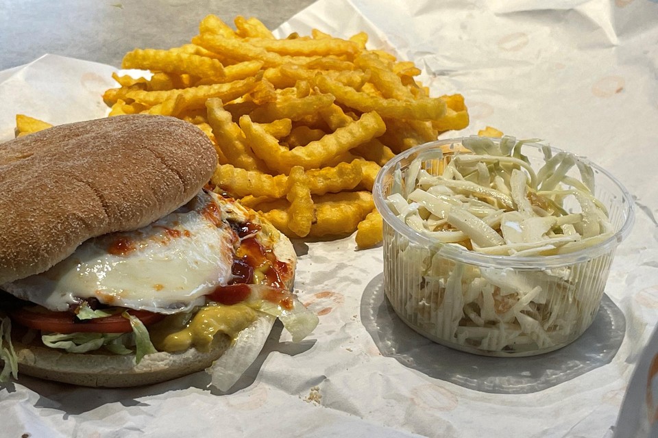 Een hamburger met frietjes, gepimpt met een spiegeleitje en koolsla.