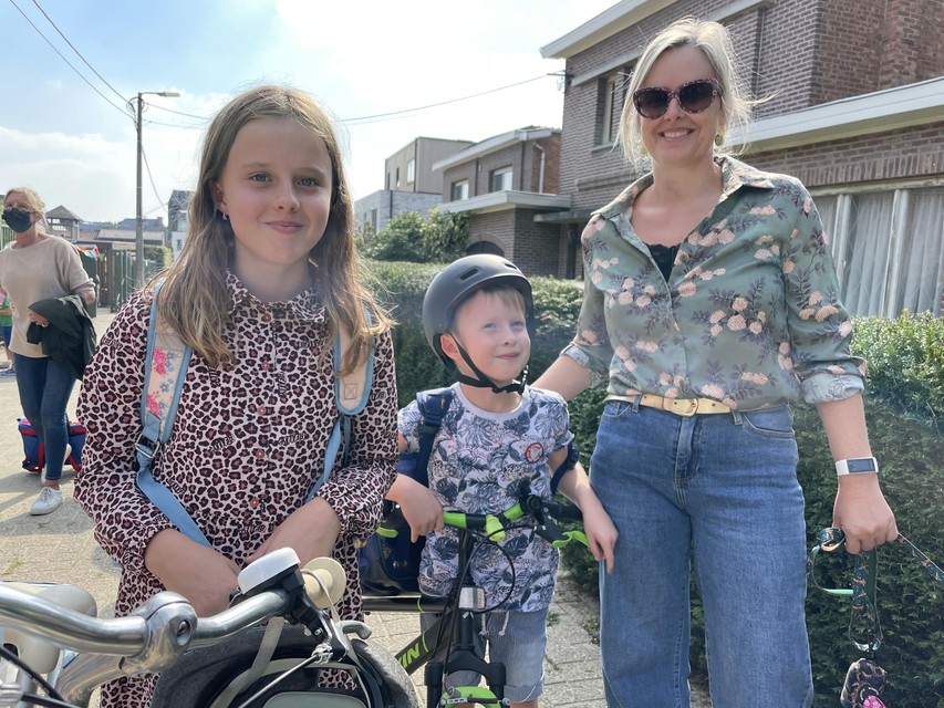Kim Lambrechts met Lola en Gus aan de schoolpoort in het Bergstraatje. “We fietsen van hieruit richting Heiststeenweg, waar nog wel toezicht is.”