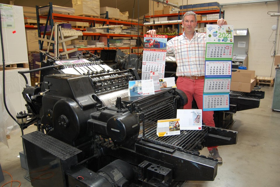 Zaakvoerder Marc Janssens bij een oude drukmachine met een hoop kalenders. Vorig jaar gingen er nog liefst 120.000 exemplaren de deur uit.