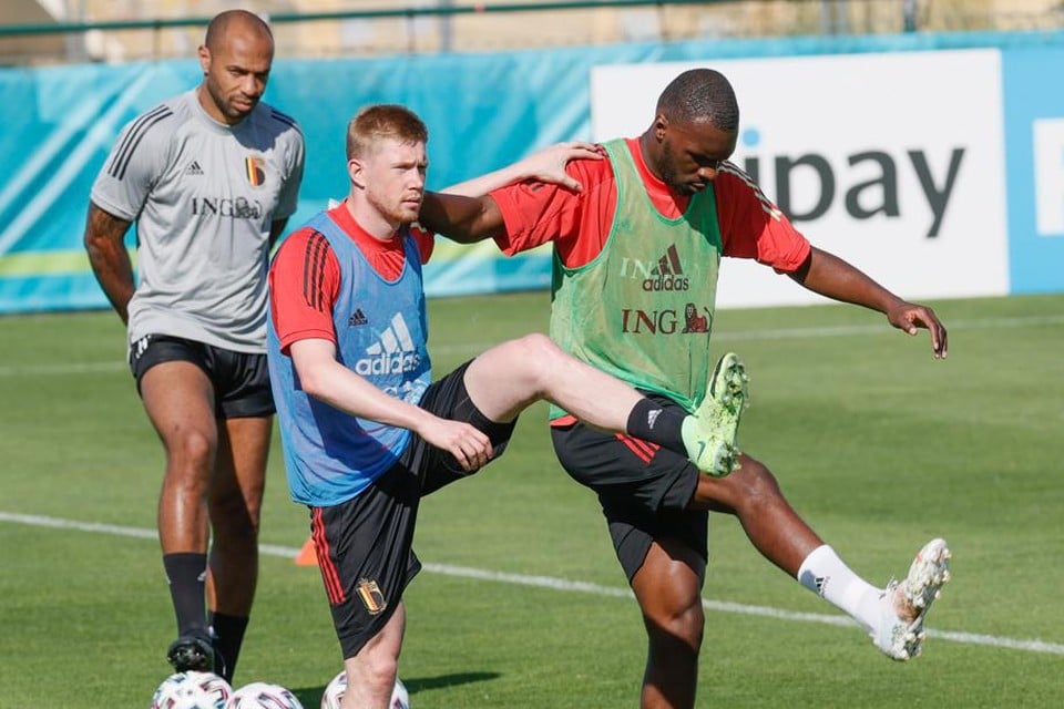 Kevin De Bruyne warmt op met Christian Benteke, T3 Thierry Henry kijkt aandachtig toe.