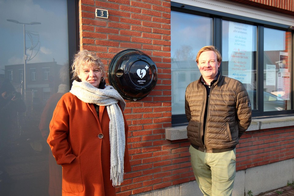 Directeur Gudrun Vanderbeck en Esmoreit De Neef tonen het AED-toestel aan de Weverstraat 3.