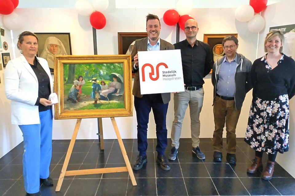 Schepenen Ann Fockaert en Arnold Wittenberg met het nieuwe logo en het aangekochte schilderij. Naast hen staan museumconservator Piet Van Deun en twee medewerkers.