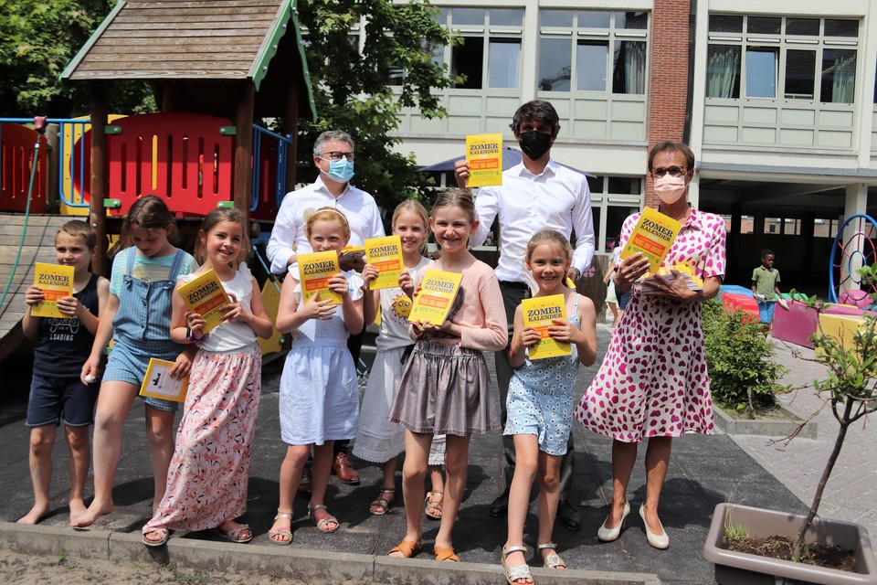 Burgemeester Koen van den Heuvel, minister Benjamin Dalle en schepen Hilde Van der Poorten delen de eerste exemplaren van de Zomerkalender uit aan de leerlingen van Sjabi.
