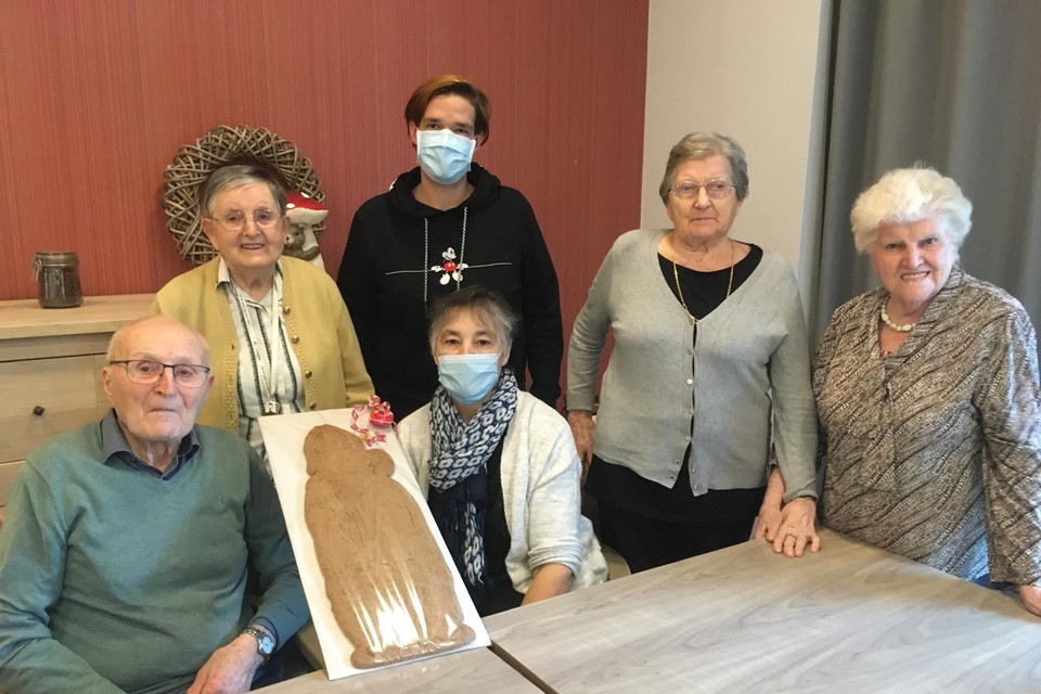 Marleen Peeters en haar dochter Anneleen (met mondmaskers) schenken een grote Sinterklaas-speculaas aan bewoners van het woonzorgcentrum Lindelo in Lille.