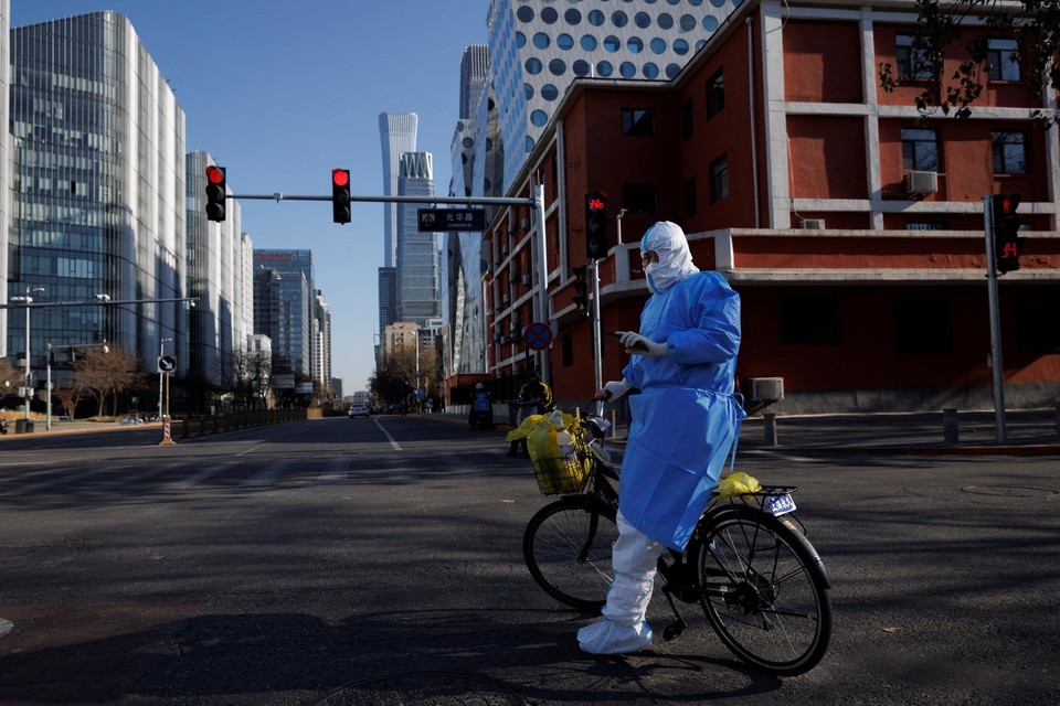 Een gezondheidswerker in beschermend pak in Peking. Het risico bestaat dat er in China, waar de bevolking minder immuniteit heeft opgebouwd, nieuwe varianten ontstaan.  