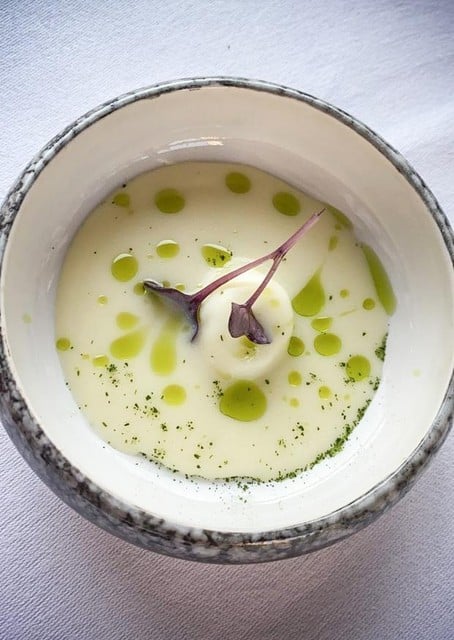Een hapje van mozzarella met een aardappelsoepje en dragonolie.