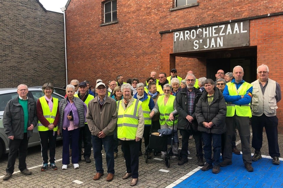 Dertig Lilse senioren staan aan de parochiezaal in Gierle klaar voor een wandeling in het dorp.