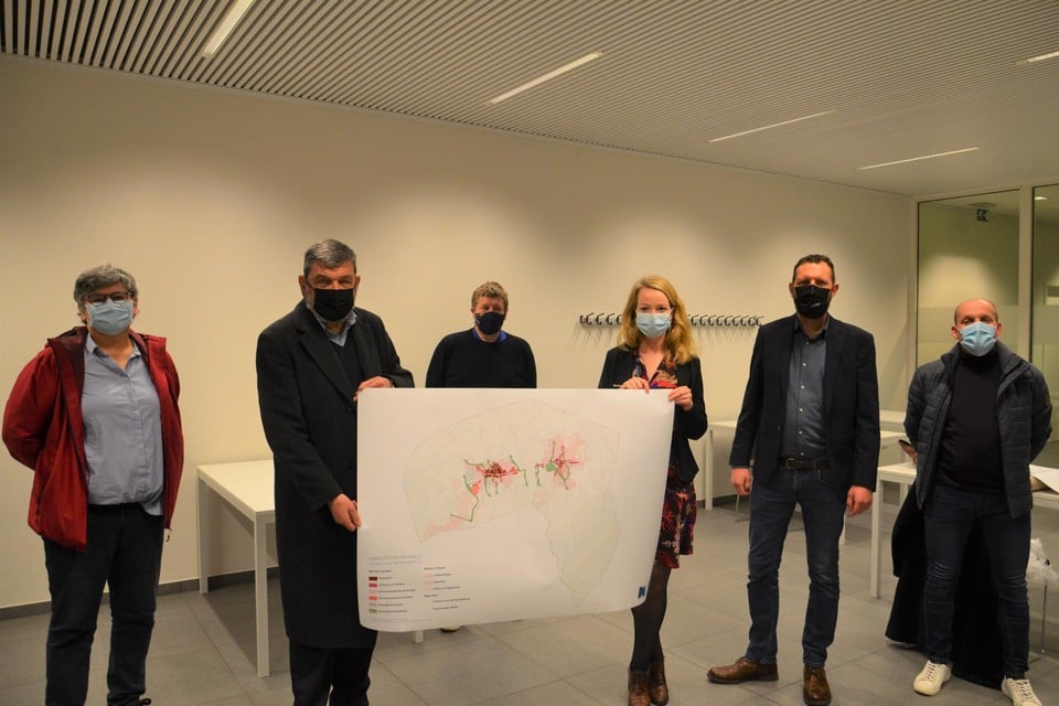 Burgemeester Harry Hendrickx (DBM) en schepen voor Ruimtelijke ordening Sanne Van Looy (N-VA) tonen de kaart met de afbakeningen, temidden van de rest van het schepencollege.