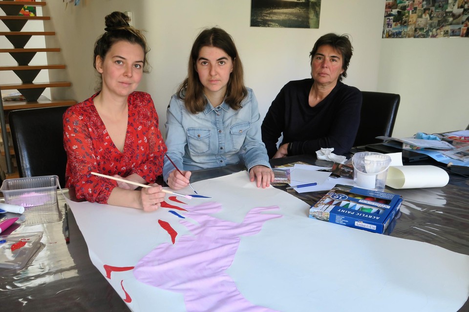 Initiatiefnemer van de petitie Carine Matheussen met haar dochters Irme en Yana, bezig met het schilderen van een grote eenhoorn om aan hun raam te hangen in de Asbroeklaan.