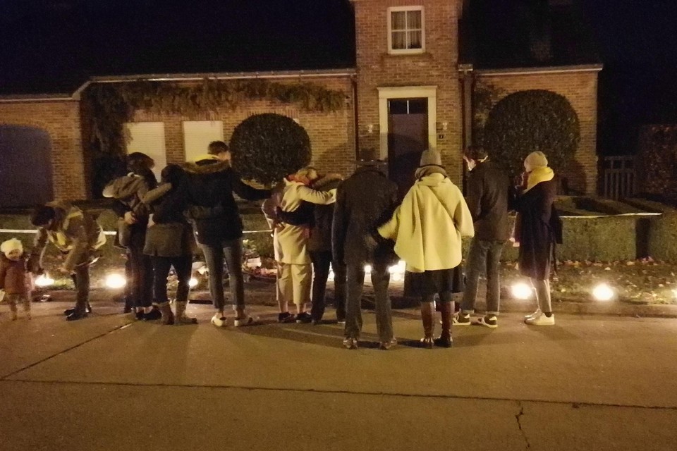 Familieleden van Mieke Verlinden zoeken steun bij elkaar voor het huis waar de zorgjuf werd omgebracht, tijdens de lichtjeswandeling van vorig jaar.