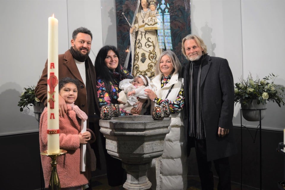 Het Oekraïens gezin Madlien, Homer en Xenia met baby Noémie boven het teruggekeerde doopvont en rechts meter en peter Katrijn en Nick uit Zoersel. 