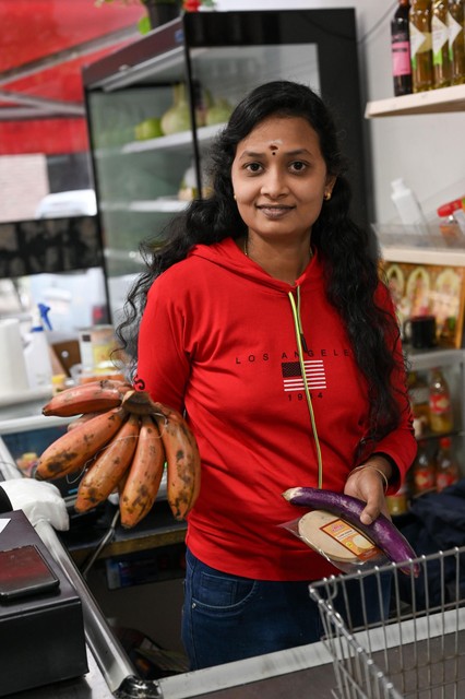 Een medewerkster van Euro Asians toont kleine, zoete banaantjes en een aubergine.