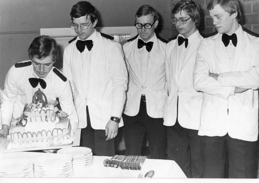 Van de beginjaren van de Hotelschool: Ronny Boonen plaatst de taart voorzichtig op de tafel. Luc Hoskens, Carlo Verreydt, Jef Liekens en Marc Dexters kijken belangstellend toe.