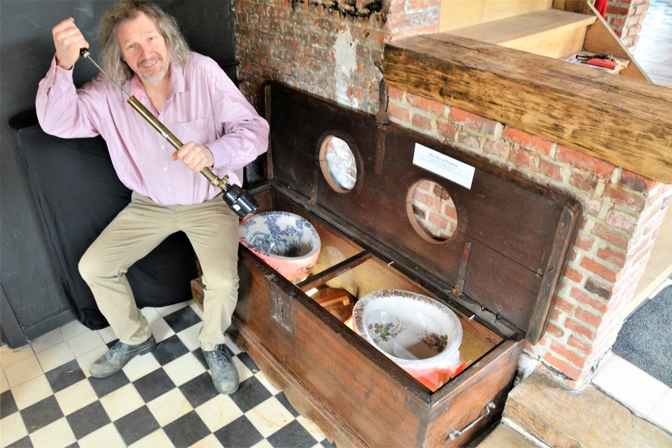 Kris Dockx bij de toiletpotten in een houten kist die dateren uit de 18de eeuw. 