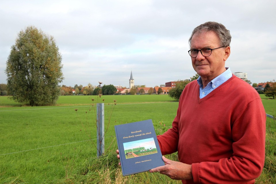 Johan toont zijn boek met Borsbeek op de achtergrond.