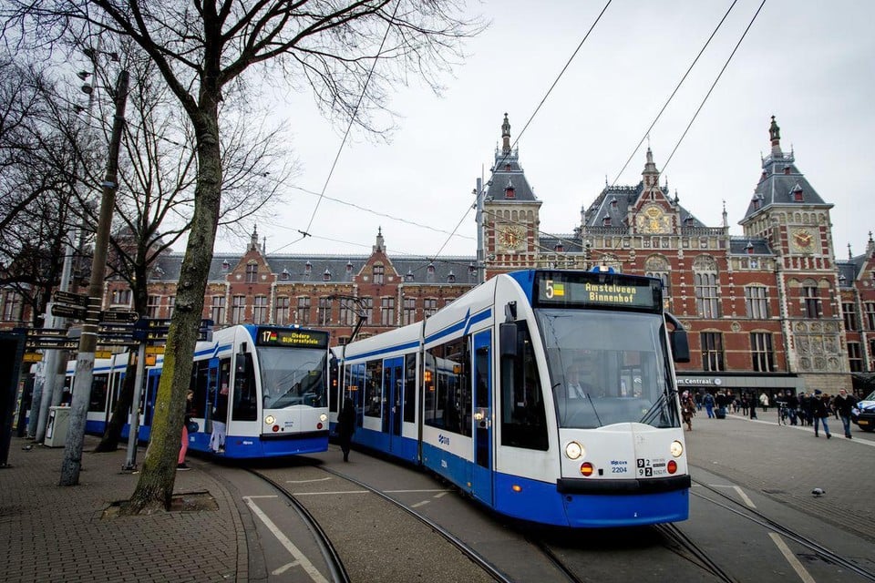Trams passeren aan het Stationsplein in Amsterdam. De gemeente heeft plannen om het doorgaand autoverkeer in de stad te weren ten voordele van het openbaar vervoer.