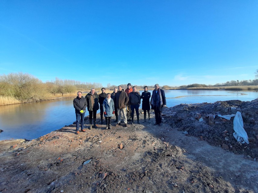 Vertegenwoordigers van de zeven projectpartners voor het al deels afgegraven gebied. Rechts zie je nog puin liggen.