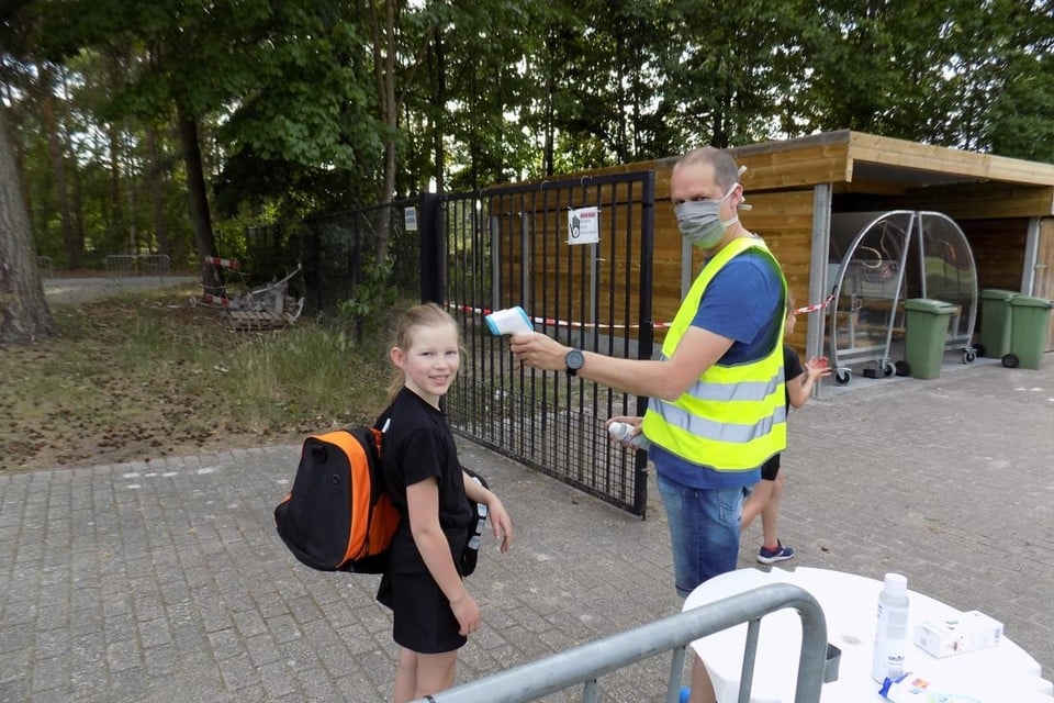 Corona-coördinator Bart Van Ossel meet aan het trainingsveld van Vobako in Lichtaart de lichaamstemperatuur van Lins Driesen.