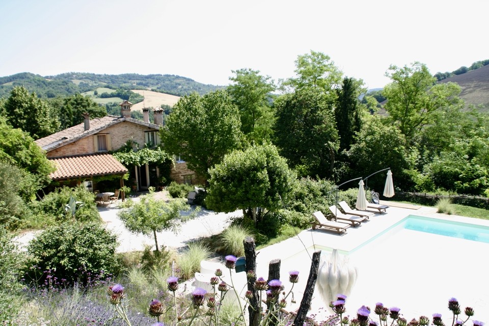 Een overzichtsbeeld van de B&B met zwembad in het uitgestrekte landschap van Petriano. 